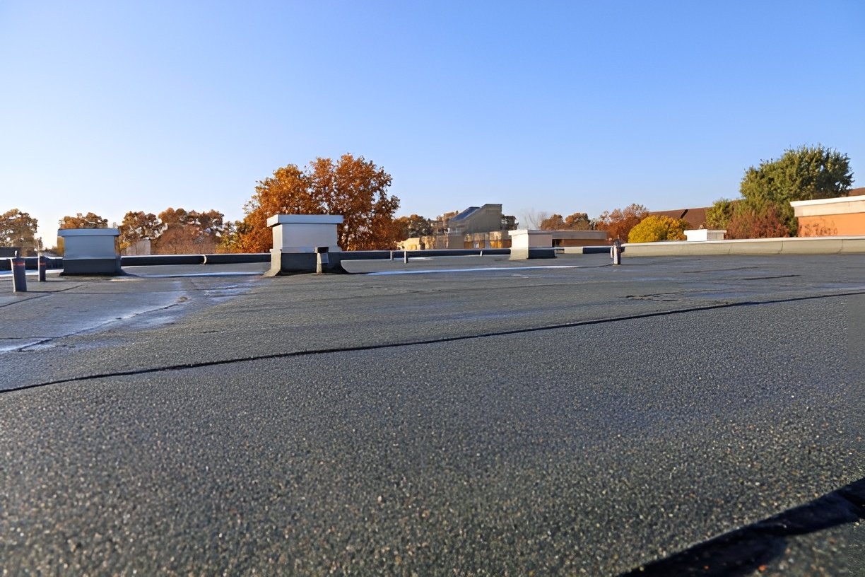 Low-slope commercial roof with protective coating and rooftop vents on a clear day. Flat roofing in Bluffton.