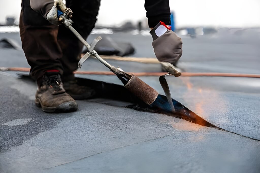 Roofer applying heat to install or seal a bitumen membrane on a flat commercial roof. Commercial roofer in Bluffton.