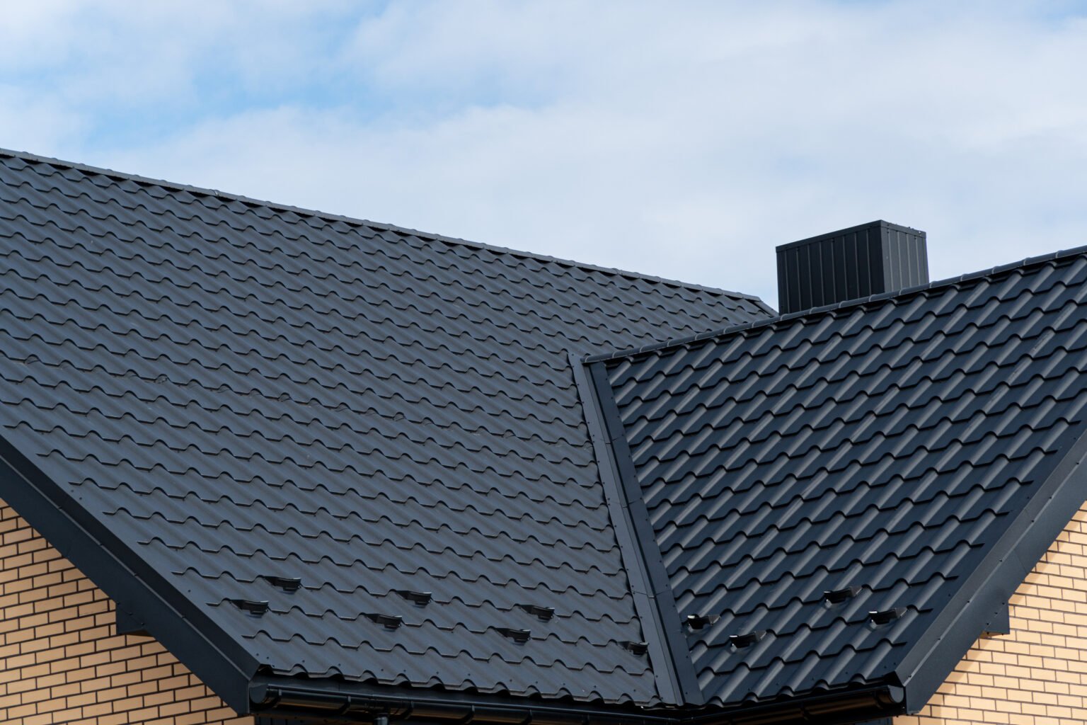 A fragment of the roof made of metal roof tiles. Modern metal roof. House roof structure. Roofing company in Hardeeville.