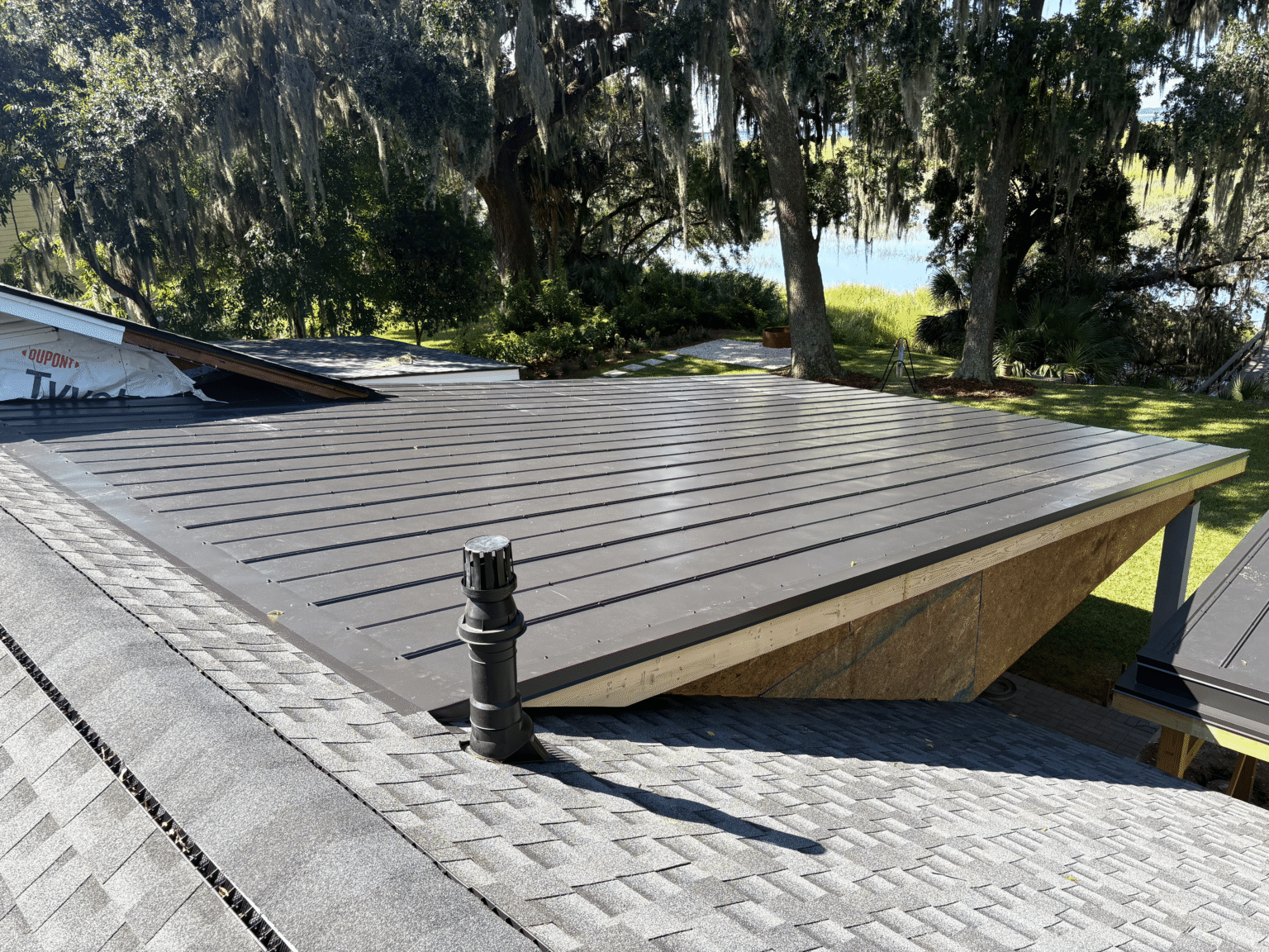 Metal roofing area next to shingle roofing. Roof vent installation in Hardeeville